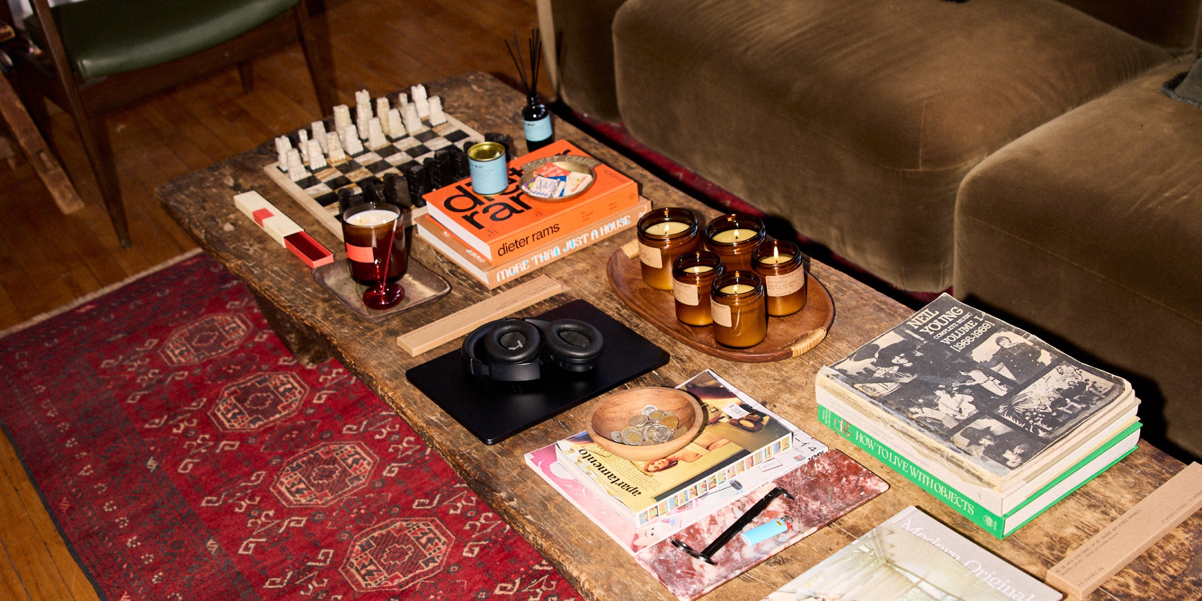 A coffee table displaying an assortment of books, magazines, and decorative Candles arranged neatly on its surface.