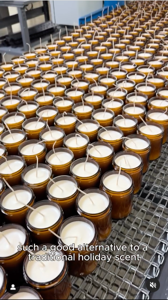 Several candles arranged in a line on a conveyor belt, ready for packaging.