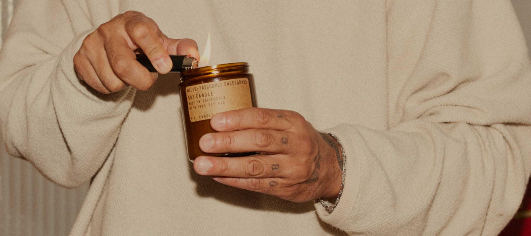 No.19 Patchouli Sweetgrass candle is being lit by person.
